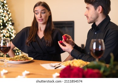 Unsuccessful Proposal Concept. Hopeful young man proposing to confused doubtful woman who is hesitating, lady looking frustrated thinking about refusal and breakup, not sure about marriage