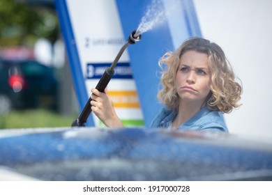 Unsure Woman Standing With Spray Foam To Clean Car