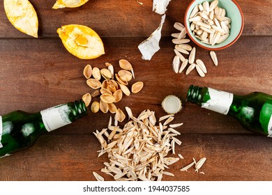 Untidy, Messy After Party Table Top View With Sunflower Seeds, Pistachios, Leftover Shells  And Orange Peels As Well As Beer Bottles On The Table. Quite A Mess After Some Night Snack Concept.