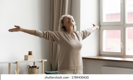 Untroubled Serene Senior Woman Standing With Arms Outstretched Closed Eyes Smiles Feels Love To Life, Welcoming New Good Day, Grateful For Happy Carefree Life, Enjoy Freedom And Comfort Living Concept