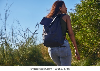 Untroubled young lady taking a casual hike along a pathway surrounded by wild flora - Shutterstock ID 1915276765