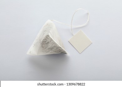 Unused Pyramid Tea Bag With Tag On White Background, Top View. Space For Text