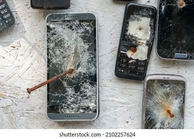 An Unusual Background Of Broken Phones Nailed To The Wall. Old Broken Phones On Display In A Mobile Phone Repair And Maintenance Workshop