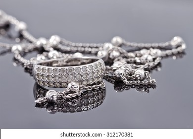 Unusual beautiful silver chain and a silver ring with gems on the reflecting surface - Powered by Shutterstock