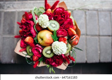 An unusual bouquet of peonies, roses, strawberries, kiwi and apples.Top view. 