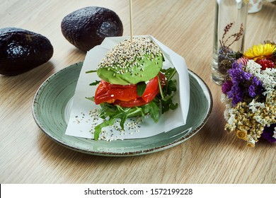 An unusual burger made from halves of avocado, like buns with tomato and ruccola, bell pepper. Close up view. Healthy and green food. Vegan - Powered by Shutterstock