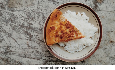 Unusual Food, Combination Of A Slice Pizza With White Rice. One Unusual Food Is A Combination Of Pizza And White Rice. 