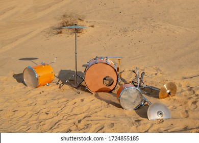 Unusual Location Selected For A Musical Instrument. Drum Set In The Sand. Individual Drums Randomly Scattered On The Sand