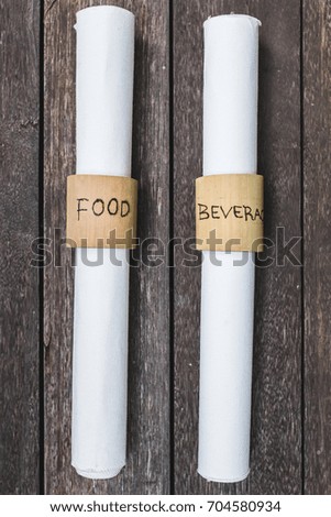 Unusual menu folded into a bundle. White menu restaurant on wooden background