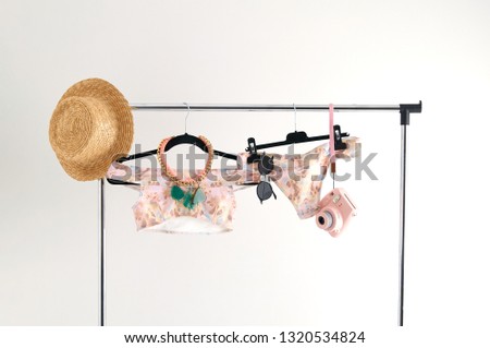 Unusual presentation of a swimsuit for buyers, fashion blog, glossy magazine, advertising, catalog. Stylish swimsuit in soft colors hanging on a hanger. A lot of accessories for a trip to luxury beach
