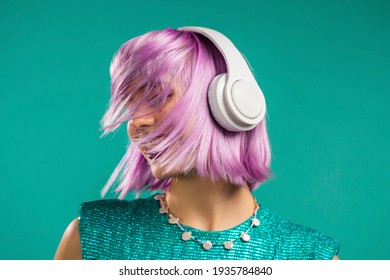 Unusual Trendy Woman With Dyed Violet Hair Listening Music, Dancing In Headphones On Turquoise Background. Fashionista Teen Girl