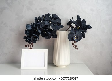 Unusual Tropical Orchid Flowers With Black Petals In Vase And Photoframe With Space For Text On Cabinet By Light Grey Wall