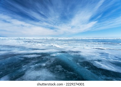 Unusual winter landscape of frozen Baikal Lake on February day. Above icy endless desert, beautiful stratus clouds adorn the blue sky. Natural cold background. Winter travel and outdoor recreation