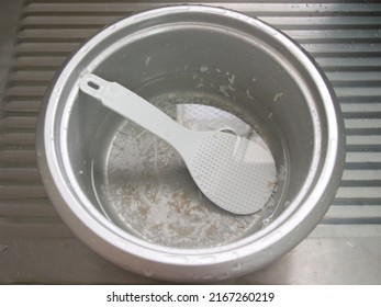 The Unwashed Rice Pot In The Empty Sink, Waiting For Someone To Come Clean The Rice Pot With A Ladle To Scoop Rice