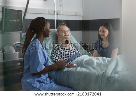Unwell suffering kid recovering in pediatric hospital ward while resting in patient bed. Nurse examining injured girl with fractured neck wearing cervical collar because of car accident. Foto stock © 