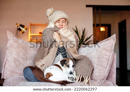 Unwell woman in blanket sit in cold living room. Suffering from lack of heat at home . Unhealthy young woman struggle from chill freeze at home. No heating concept