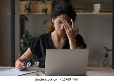 Unwell Young Caucasian Woman Work On Computer At Home Office Take Off Glasses Suffer From Migraine Or Headache. Unhappy Tired Millennial Female Struggle With Dizziness Or Blurry Vision Using Laptop.