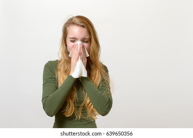 Unwell Young Woman Blowing Her Nose On A White Tissue Conceptual Of Seasonal Flu And Colds, Allergy, Rhinitis Or Hayfever, Head And Shoulders On White