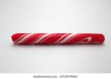 Unwrapped peppermint polkagris stick candy cane sugar vintage candy bar roll on white background