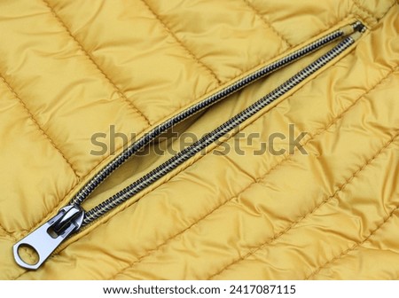 Unzipped metal zipper on the pocket yellow jacket close-up