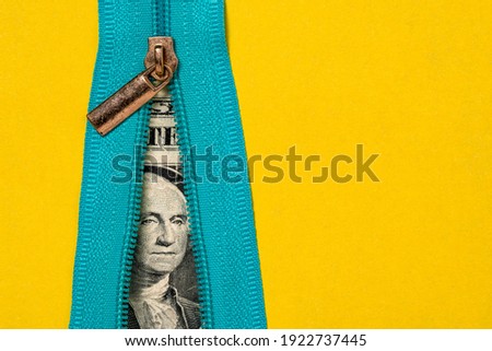 Unzipping a blue zipper on yellow background and finding money. Concept of money and secret.