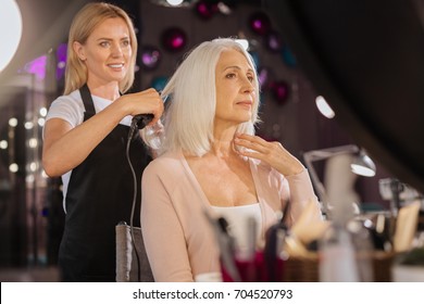 Upbeat hairdresser straightening hair of a senior woman - Powered by Shutterstock