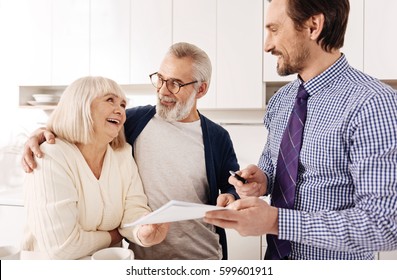 Upbeat Old Couple Consulting With Financial Adviser At Home