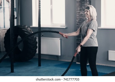 Upbeat Senior Woman Exercising With Battle Ropes