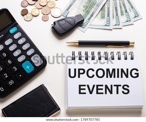 UPCOMING EVENTS are\
written in a white notepad next to a calculator, car key, money and\
pen. Business concept