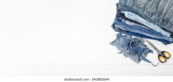 Upcycle Old Denim Garbage. Recycling Blue Jeans Cut Pieces, Sewing And Home Needlework. Recycling And Scissors On White Background. Circular Economy. Zero Waste Banner With Copy Space. DIY Concept