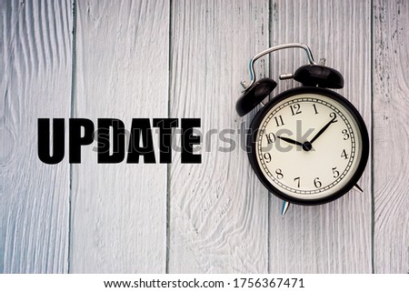 UPDATE text and alarm clock on wooden background. Business Concept