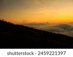 An uphill hiking trail at dawn with clouds behind