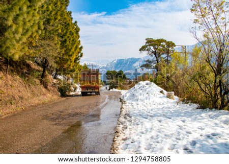 Uphill road in winter at banikhet dalhousie himachal pradesh india. Scenic winter view from the asphalt road covered with snow and treess on the side of road on blue sky background and clouds