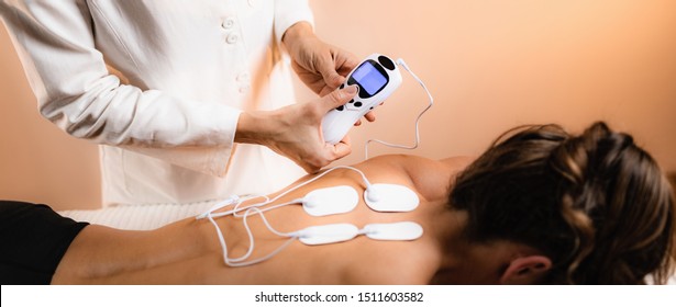 Upper Back Physical Therapy with TENS Electrode Pads, Transcutaneous Electrical Nerve Stimulation. Therapist Positioning Electrodes onto Patient's Upper Back