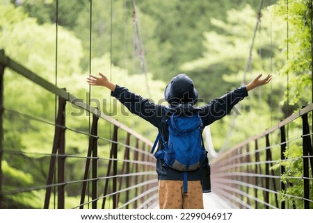 Upper body cut of a child taking a deep breath at the entrance of a suspension bridge while climbing a mountain in Japan Faceless and easy to use for summer vacation, leisure and outdoor images Copy s