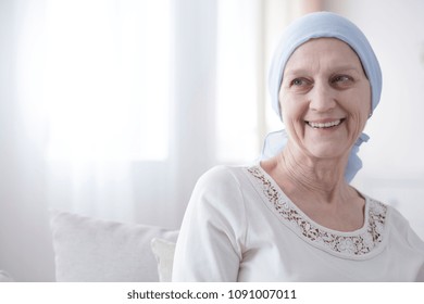 Upper Body Portrait Of An Older, Female Cancer Patient Looking Happy And Hopeful In A Bright White Interior