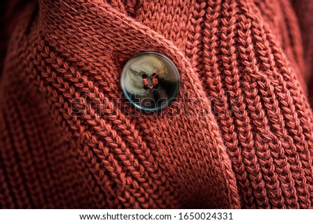 Upper button of a natural wool knitted cardigan