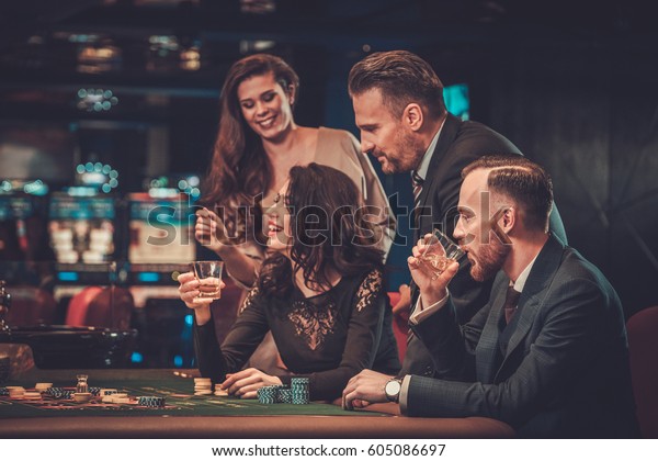Upper class friends\
gambling in a casino.