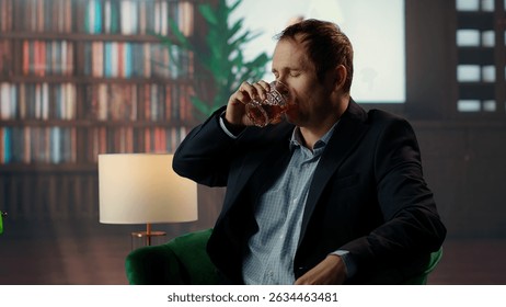 Upper class member drinking too much scotch whiskey with his friend at the elite vintage social club, getting hiccups due to high alcohol levels from the strong drink. Tipsy gentlemen. Camera B.