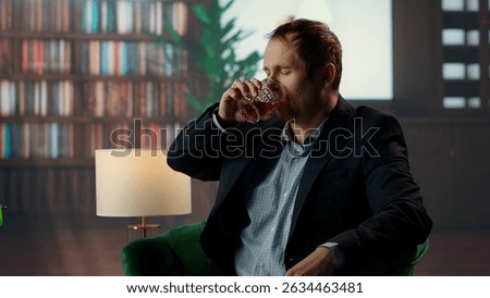 Upper class member drinking too much scotch whiskey with his friend at the elite vintage social club, getting hiccups due to high alcohol levels from the strong drink. Tipsy gentlemen. Camera B.