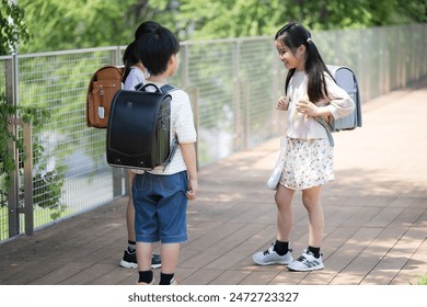Upper half of a girl in the same class with her school bag on her back, talking with her friends in a friendly manner