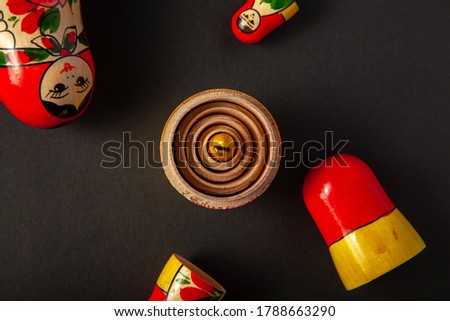 Upper halves of wooden russian dolls are scattered randomly while lower haves were put together in a concentric fashion with the smallest doll of the set sitting in the center.