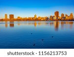 Upper Manhattan skyline view with reflection in big lake  with ducks and in sunset lights during the fall autumn season. Central park in New York, NY, USA