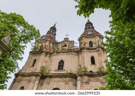Upper part of main facade of dilapidated Baroque St. Anthony's Church of the Bernardine Monastery of the 18th century in Hvizdets, Ukraine, view from bottom to top in overcast day