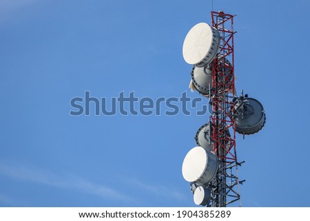 The upper portion of a communications tower holds an array of several microwave backhaul antennas with protective radome covers, giving them the appearance of a bass drum.