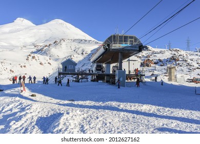 The upper station of the cable car at the ski resort. On the background there is a blue sky and mountain peaks. The concept of active winter recreation