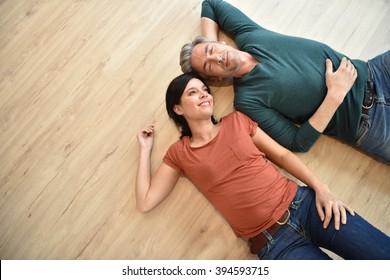 Upper View Of Couple Laying On Wooden Floor