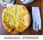 Upper view of freshly baked Imeretian khachapuri on wooden table. Traditional Georgian flatbread topped with sulguni cheese