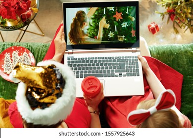 Upper view of modern mother and child sitting on couch in the modern living room at Christmas watching Christmas movie on laptop.