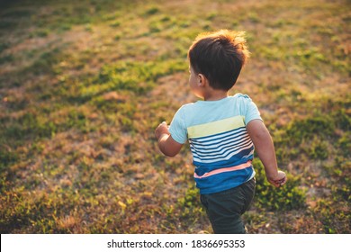 Upper view photo of a caucasian boy playing and running on a field during a summer evening